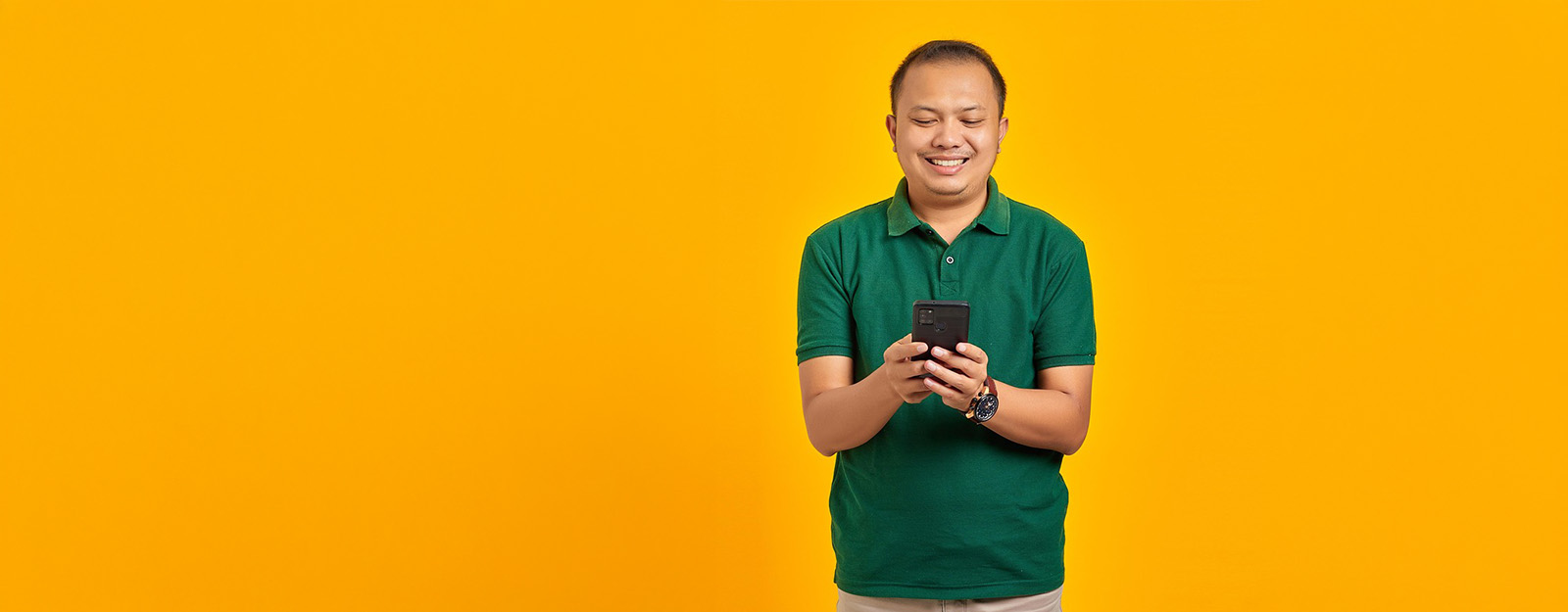 Image of a middle aged man dressed in a polo looking at his phone and smiling.
