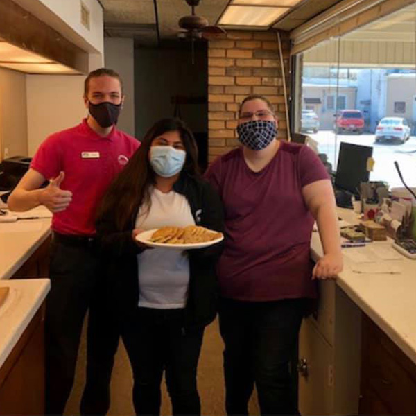 Three tellers from the Newton Drive location holding a plate of cookies.