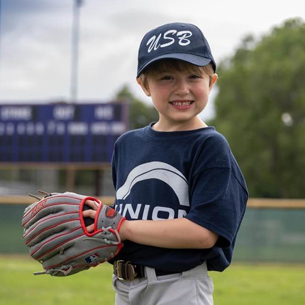Photo of a young baseball player wearing a Union State Bank team uniform. Photo by The Focused Image Photo.