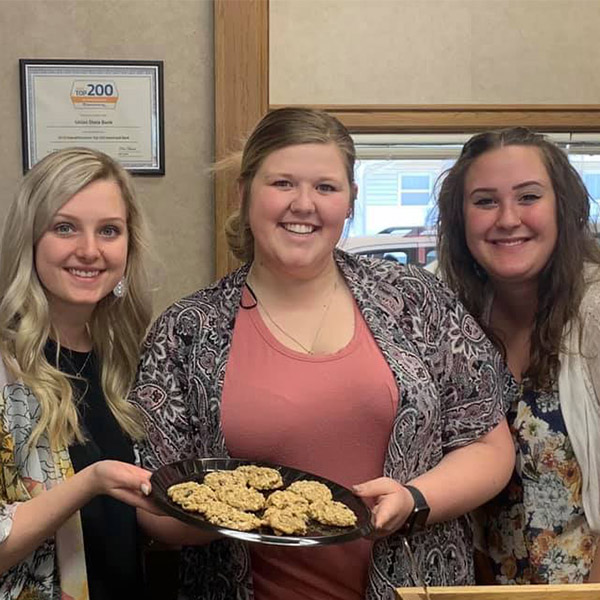 Three tellers from the Ark City North location holding a plate of cookies.