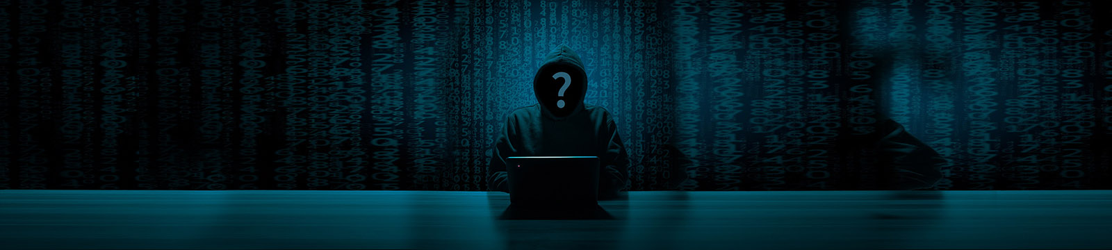 Image of hooded mystery person sitting in front of a laptop with a shadowed background.