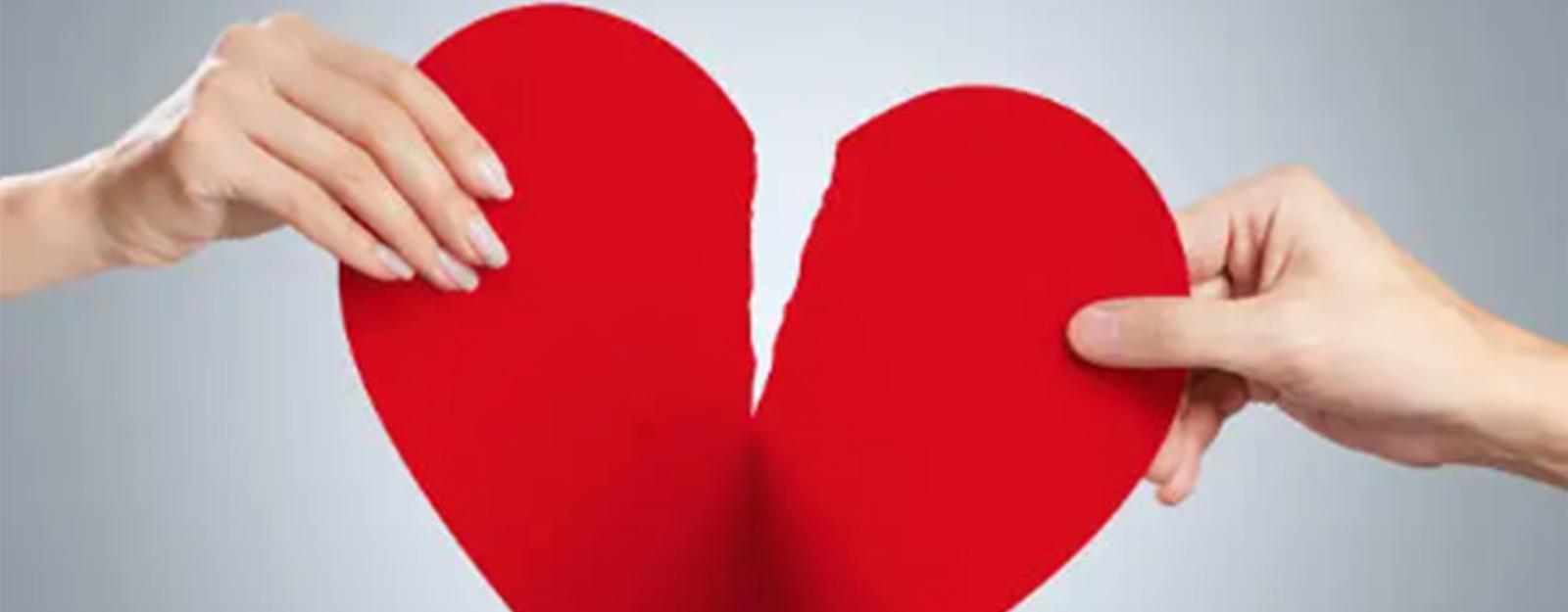 Image of two hands pulling in opposite directions resulting in the tearing of a paper heart.