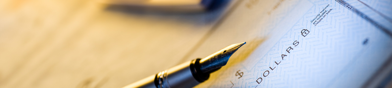 Photo of an ink pen on top of a blank check.