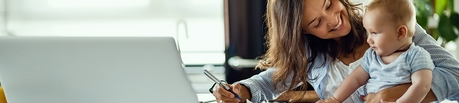 Image of woman holding infant in front of computer