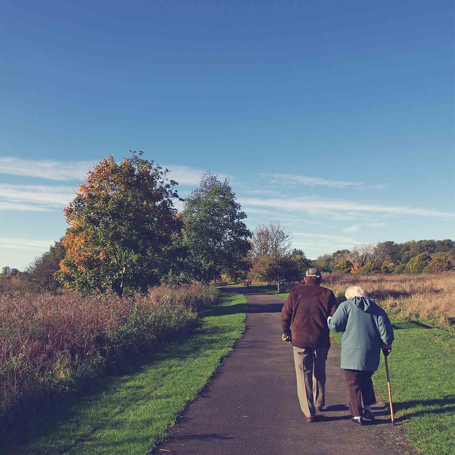 Photo of an elderly couple walking down a path together.