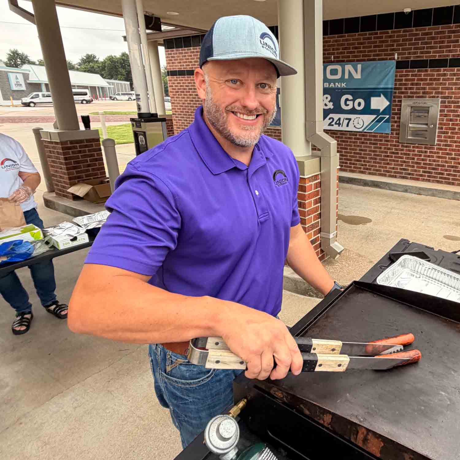 Photograph of Union State Bank Arkansas City Market President Zack Stoy grilling hot dogs for a customer appreciation event.