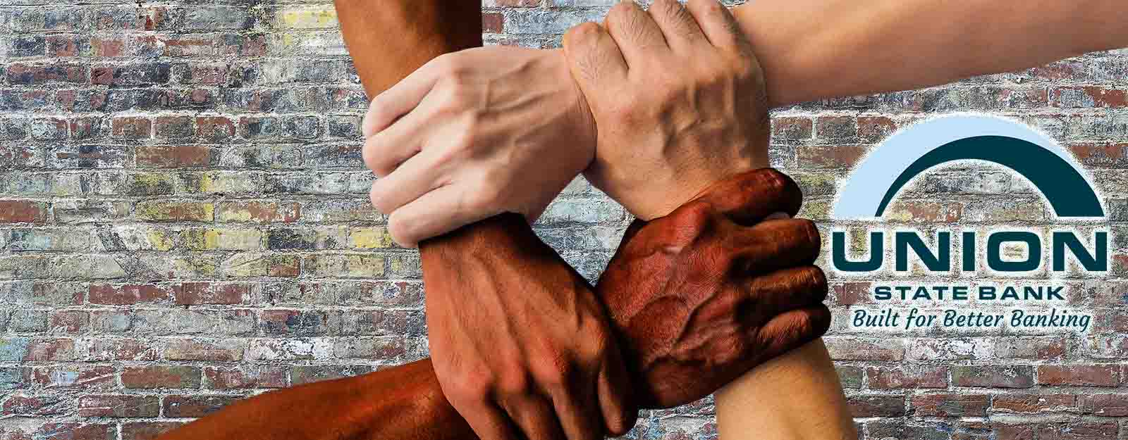 Photo of four interlocking arms in front of a brick wall background with the union state bank logo.