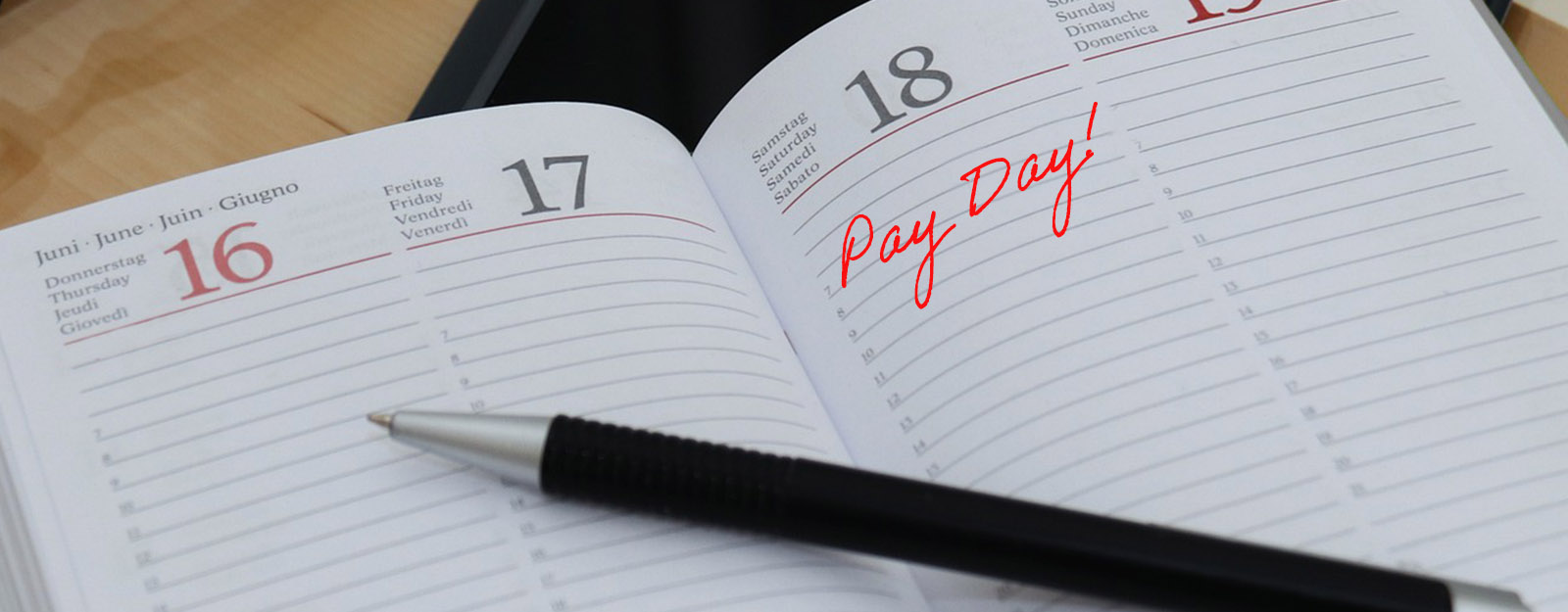 Image of a calendar planner with the words "Pay Day" written over a date.