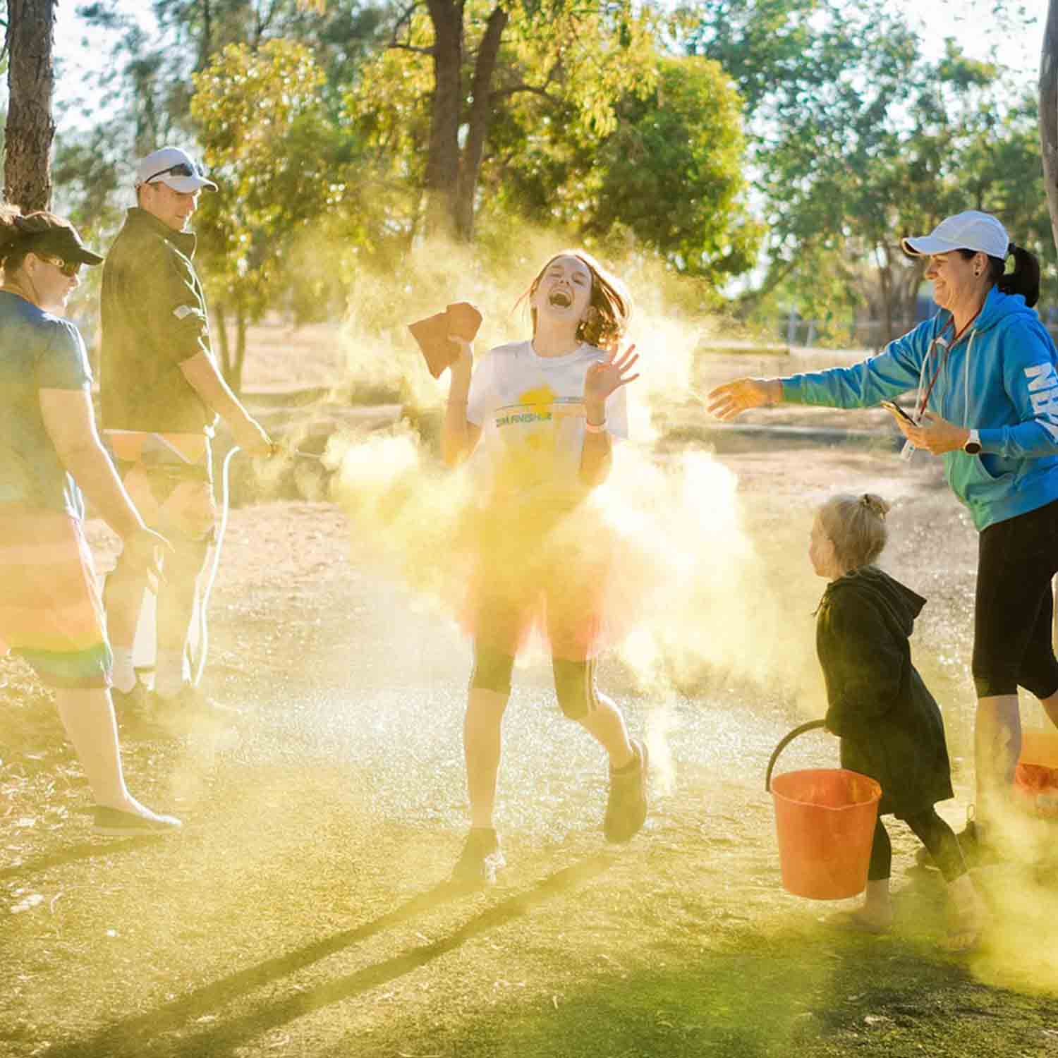Image of a family within the woods throwing chalk dust to celebrate a young runner.