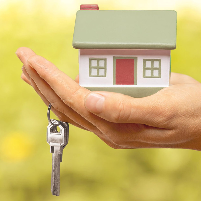 Photo of hand holding a model house in open palm with keys hanging off of a finger.