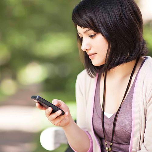 Young woman sitting outside looking at her phone.