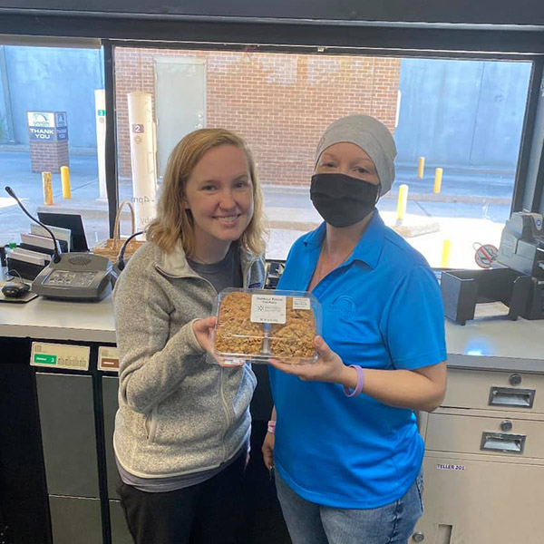 Three tellers from the Winfield Drive location holding a box of cookies.