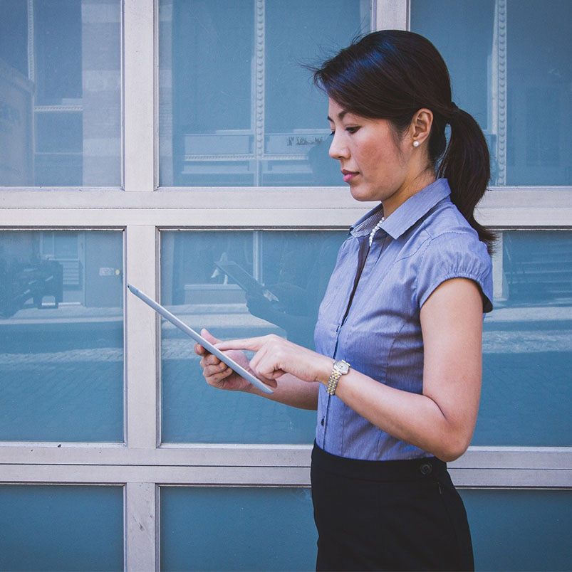 Woman standing in front of business using a tablet.