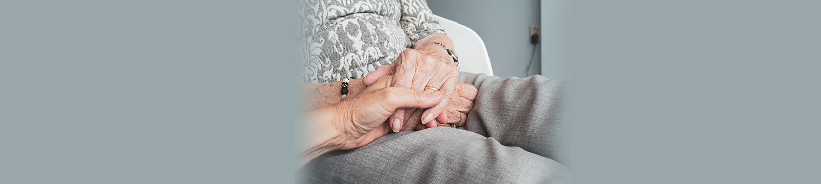 Close up photograph of an elderly person holding a younger individual's hand.