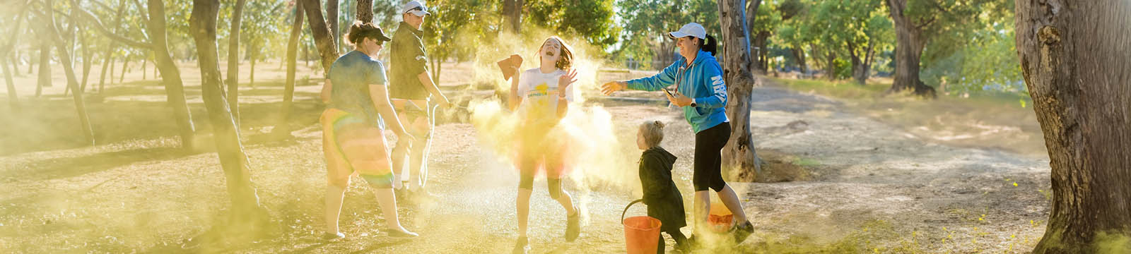 Image of a family within the woods throwing chalk dust to celebrate a young runner.