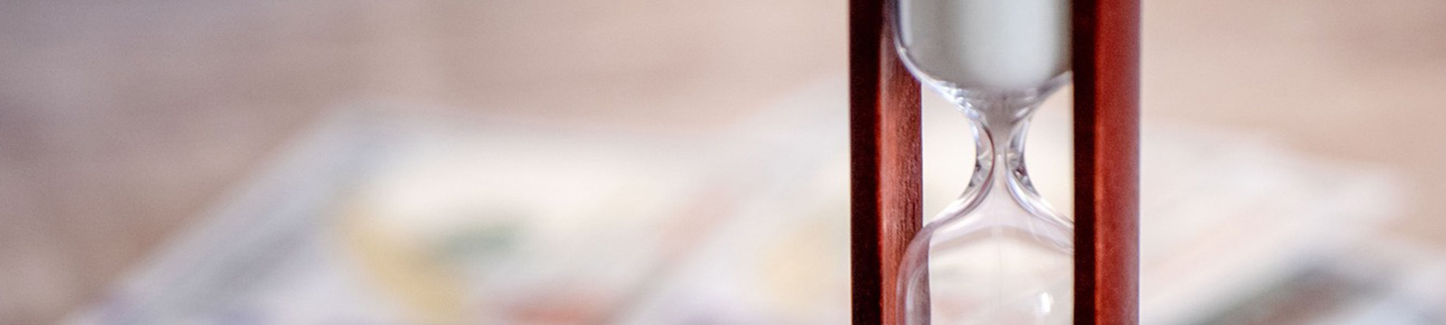 Photo of an hour glass beside a pile of money.