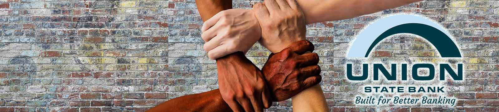 Photo of four interlocking arms in front of a brick wall background with the union state bank logo.