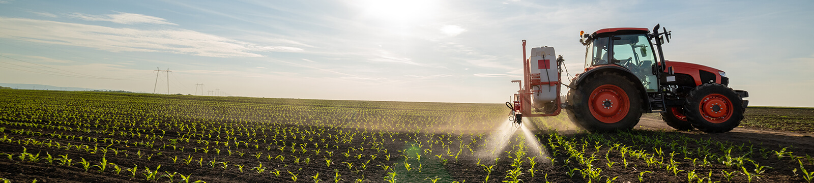 Tractor in a field with the sun behind