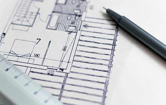 Close up photo of blueprints, ruler, and a pen.