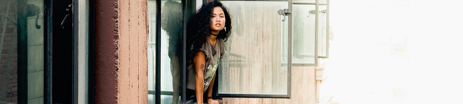 Photo of a young woman leaning out of an apartment window.