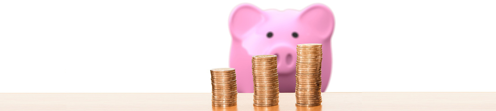 Image of stacks of pennies with a large pink piggy bank in the background.
