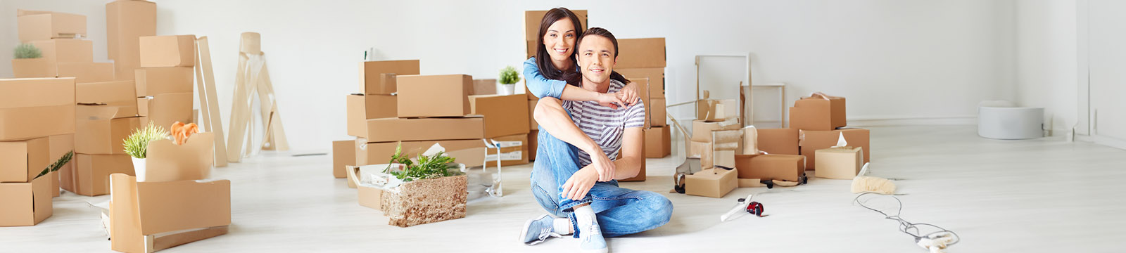 Photo of young couple surrounded by unpacked moving boxes.